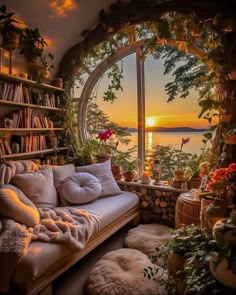 a living room filled with furniture and a large window looking out onto the water at sunset