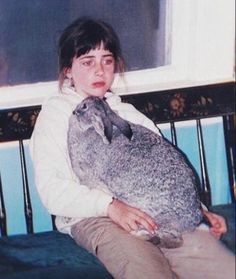 a woman sitting on a couch holding a cat