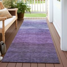 a purple rug is on the porch next to a chair and potted plant in front of an open door