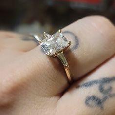 a close up of a person's hand with a diamond ring on their finger