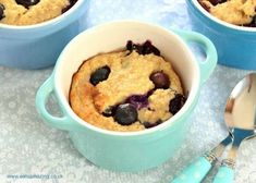 blueberry cobbler in a bowl with spoons next to it on a table