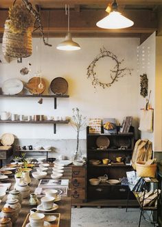 a room filled with lots of plates and bowls on top of a wooden table next to shelves