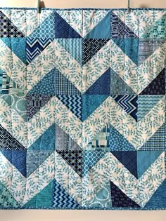 a blue and white quilt hanging on a wall