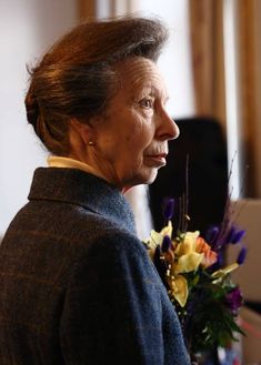 an older woman holding a bouquet of flowers in her hand and looking off into the distance