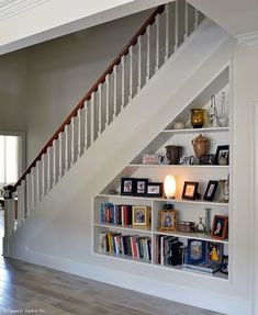 a bookshelf in the corner of a room under a stair case