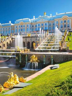 a large building with fountains in front of it and green grass on the ground below