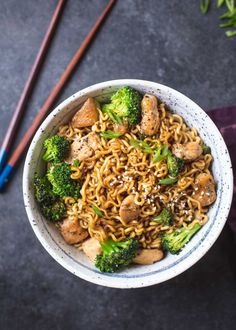 a bowl filled with noodles and broccoli next to chopsticks on a table