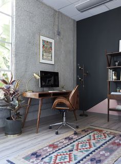 a desk with a computer on top of it next to a potted plant and bookshelf