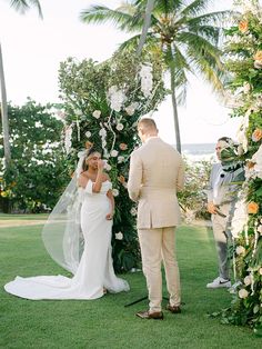 the bride and groom are getting married in front of an arch with flowers on it