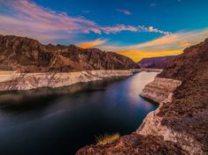 the sun is setting over a large lake in the middle of mountains and desert land