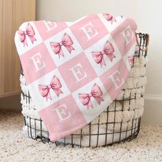 a blanket with pink bows on it sitting in a basket