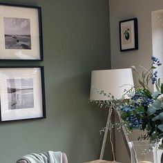 a living room with pictures on the wall and vases filled with flowers in it