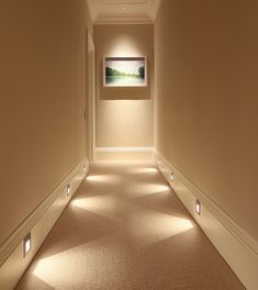 an empty hallway with lights on the wall and carpeted floor in front of it