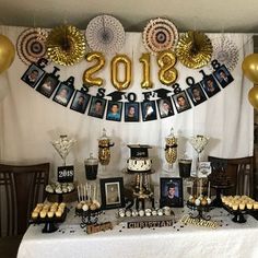 a table topped with pictures and balloons next to a white table cloth covered in black and gold decorations