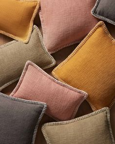 many different colored pillows on top of each other, one is brown and the other is pink