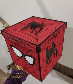 a spiderman mask hanging from the side of a wooden sticker box on a wall