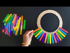 a person holding a wooden circle with colored sticks in front of it and an object made out of popsicle sticks