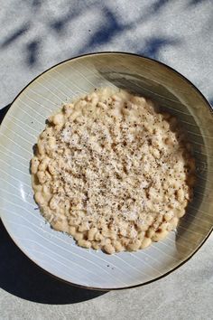 a bowl filled with macaroni and cheese on top of a white plate next to a sidewalk