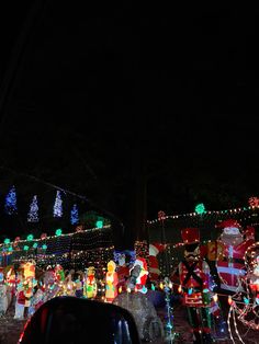 a house covered in christmas lights with santa clause decorations on the front and side of it