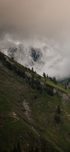 the mountains are covered in clouds and trees