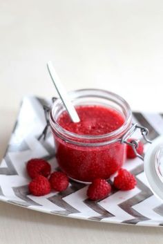 a jar filled with raspberry jam on top of a white and gray napkin