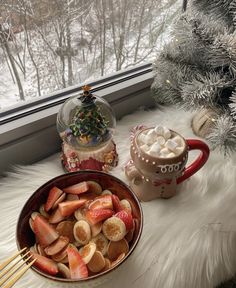 a bowl of strawberries and marshmallows next to a cup of hot chocolate