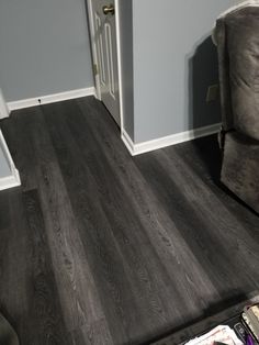 a living room with gray walls and wood flooring on the floor, next to a recliner