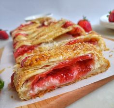 a pastry with strawberries on it sitting on a cutting board next to some other food