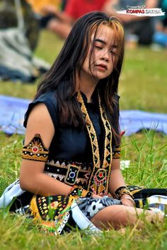 a woman sitting in the grass with her eyes closed