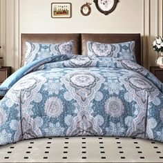 a bed with blue and white comforters in a bedroom next to a clock on the wall