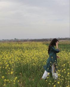 a woman walking through a field with yellow flowers