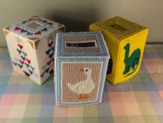 two small boxes sitting on top of a checkered tablecloth covered table cloth with animals and letters painted on them