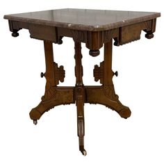 an old wooden table with marble top and two pedestals on one end, against a white background