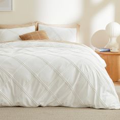 a bed with white comforter and pillows in a bedroom