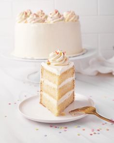 a slice of cake on a white plate with a gold fork and sprinkles