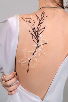 the back of a woman's shoulder with flowers on it and leaves drawn in white ink