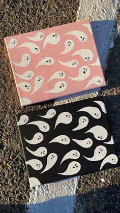 two canvases with ghost faces painted on them sitting on the ground next to each other