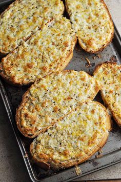 four pieces of bread sitting on top of a baking pan filled with cheese and other toppings