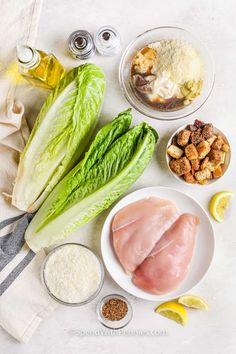 lettuce, chicken, and other ingredients on a white counter top with lemons