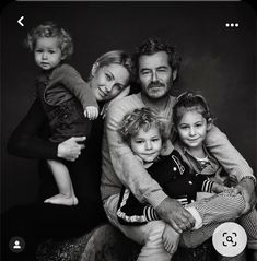 a black and white photo of a family posing for a portrait with the child on his lap