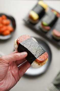 a person is holding up a sushi roll