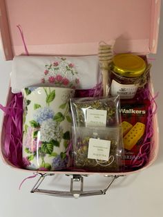 a pink suitcase filled with tea, cookies and other items