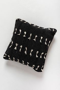 a black and white pillow sitting on top of a white wall