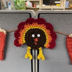 there is a crocheted turkey head hanging on the clothes line in an office cubicle