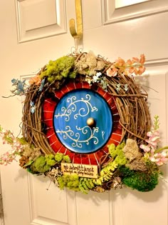 a wreath with a clock on it hanging from the front door, decorated with flowers and plants