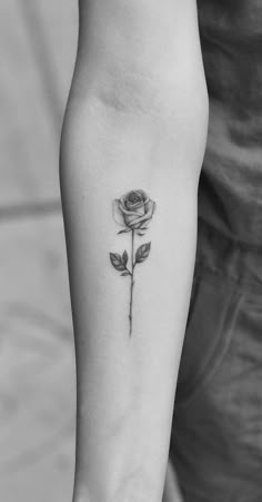 a black and white photo of a rose tattoo on the arm