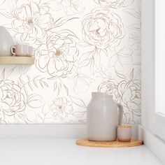 a white vase sitting on top of a counter next to a cup and saucer