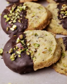 chocolate covered cookies with pistachios and almonds on the top one is cut in half