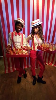 two people dressed in red and white holding trays with food on them while standing next to each other