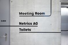 the door to an office building is labeled in black and white letters that read meeting room, netrics ag toilets